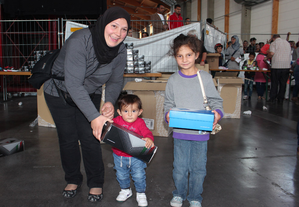 Diese Mutter freut sich mit ihren beiden Kindern über das neue Schuhwerk