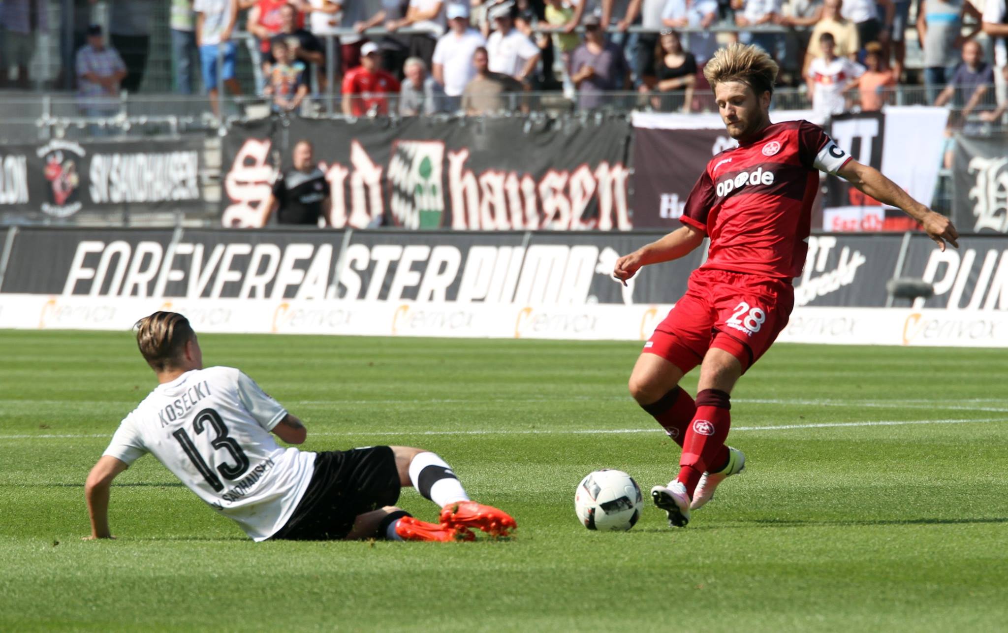 Sandhausens Jakub Kosecki (li.) mit einer Grätsche gegen Lauterns Kapitän Daniel Halfar