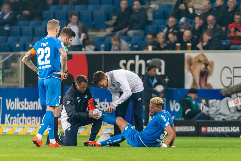 Mannschafts-Arzt Dr. Ralph Kern (verdeckt) und Physio Peter Geigle behandeln den verletzten linken Fuß von Joelinton. Der Brasilianer konnte gegen Leverkusen trotzdem nicht mehr weiterspielen.