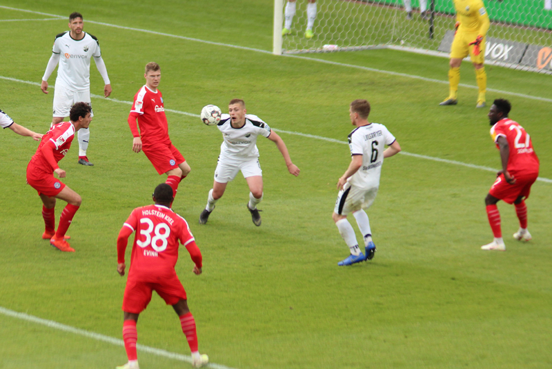 Zhirov versucht, mit letztem Einsatz den Ball vor den drei Kieler Gegenspielern aus der Gefahrenzone zu befördern